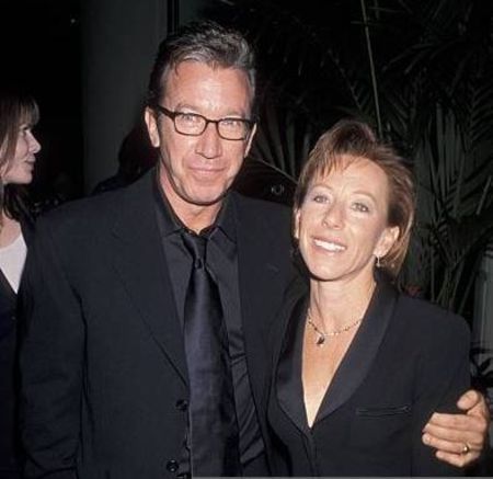 Tim Allen in a black suit poses a picture with wife Laura Deibel.